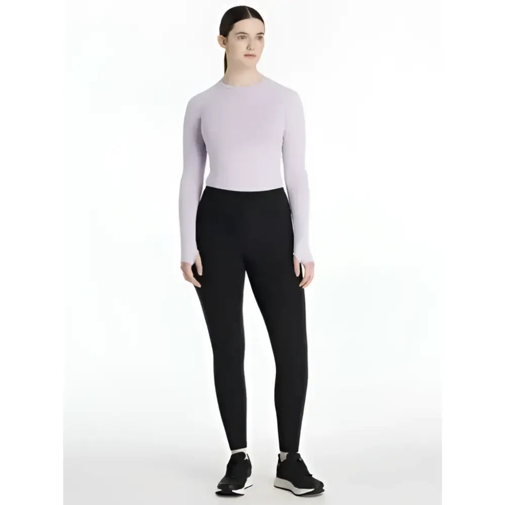 A woman wearing lemieux natalie’s brush black pull on leggings paired with a lavender long sleeve top and black shoes