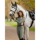 A white horse with a black bridle and saddle alongside lemieux philippa mesh base layer rosemary product view