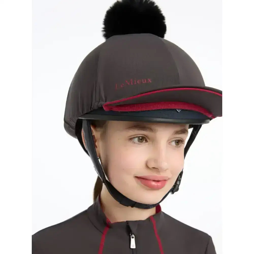 Black lemieux pippa hat with fluffy pom-pom, red trim, silky smooth four-way stretch in hat silk cinder fabric