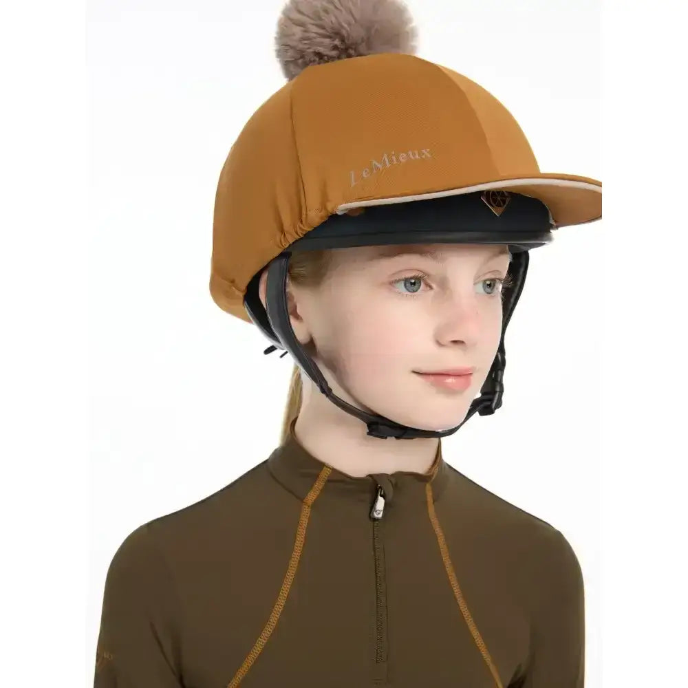 A tan lemieux pippa hat silk ginger with a fluffy brown pom-pom and jennieux embroidered in gold thread