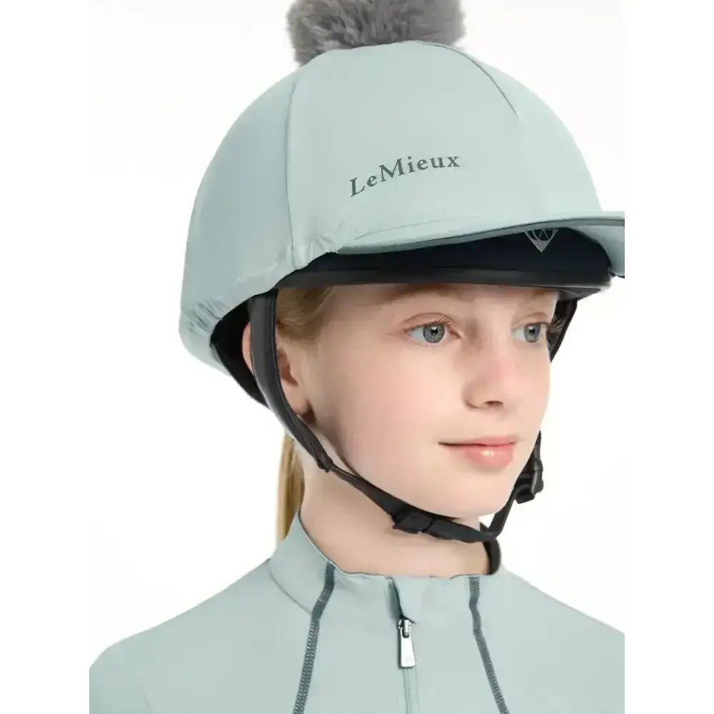 Light blue lemieux pippa hat silk glacier equestrian helmet with gray faux fur pom-pom and silky smooth four-way fabric