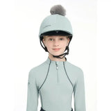 Light blue lemieux pippa hat silk equestrian helmet with gray faux fur pom-pom and silky smooth four-way fabric