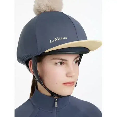 Navy blue lemieux pom hat with beige brim and fluffy pom pom in silk dusk mimosa equestrian helmet cover