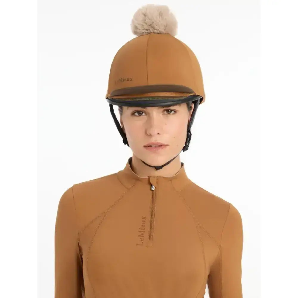 Tan lemieux pom hat silk ginger equestrian helmet with fluffy beige pom-pom and black trim in silky smooth four-way fabric