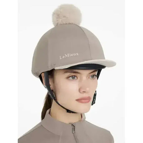 Beige lemieux pom hat silk pecan stone equestrian helmet cover with a fluffy pom hat silk on top