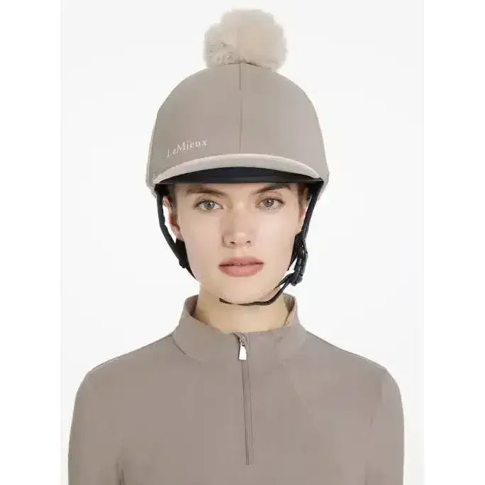 A taupe lemieux pom hat silk pecan stone with a soft fluffy pom pom and white embroidered brand name