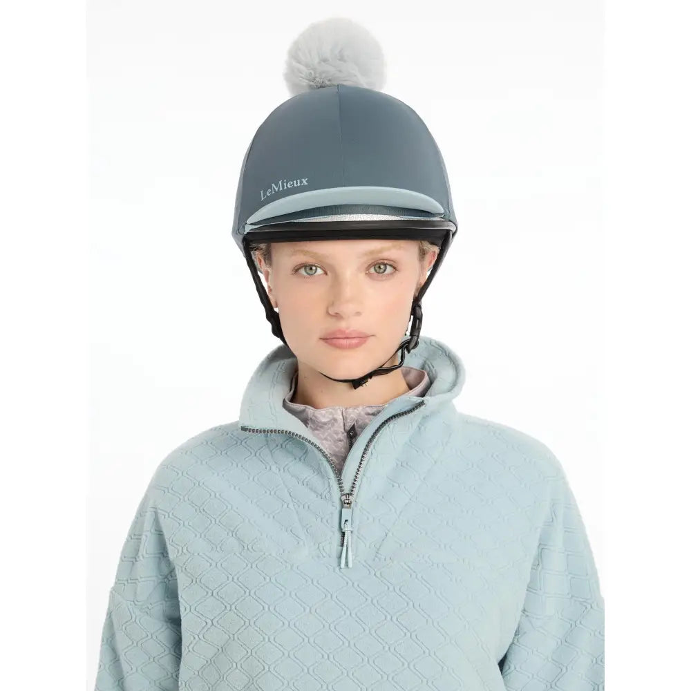 A sleek matte gray lemieux pom hat with a soft white pom pom made of silky smooth four way hat silk petrol material