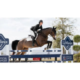 A brown horse jumping over an obstacle wearing a lemieux puissance suede white suede cc pad close contact saddle pad