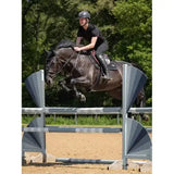 A dark brown horse mid-jump wearing lemieux puissance suede close contact black square saddle pad