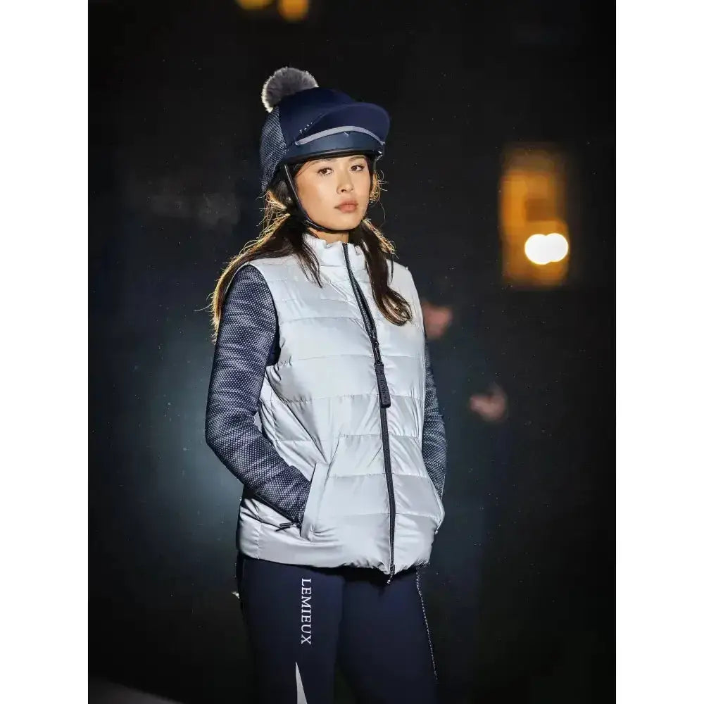 Silver puffer vest with mesh sleeves and black zipper paired with lemieux reflective hat silk co-ordinate