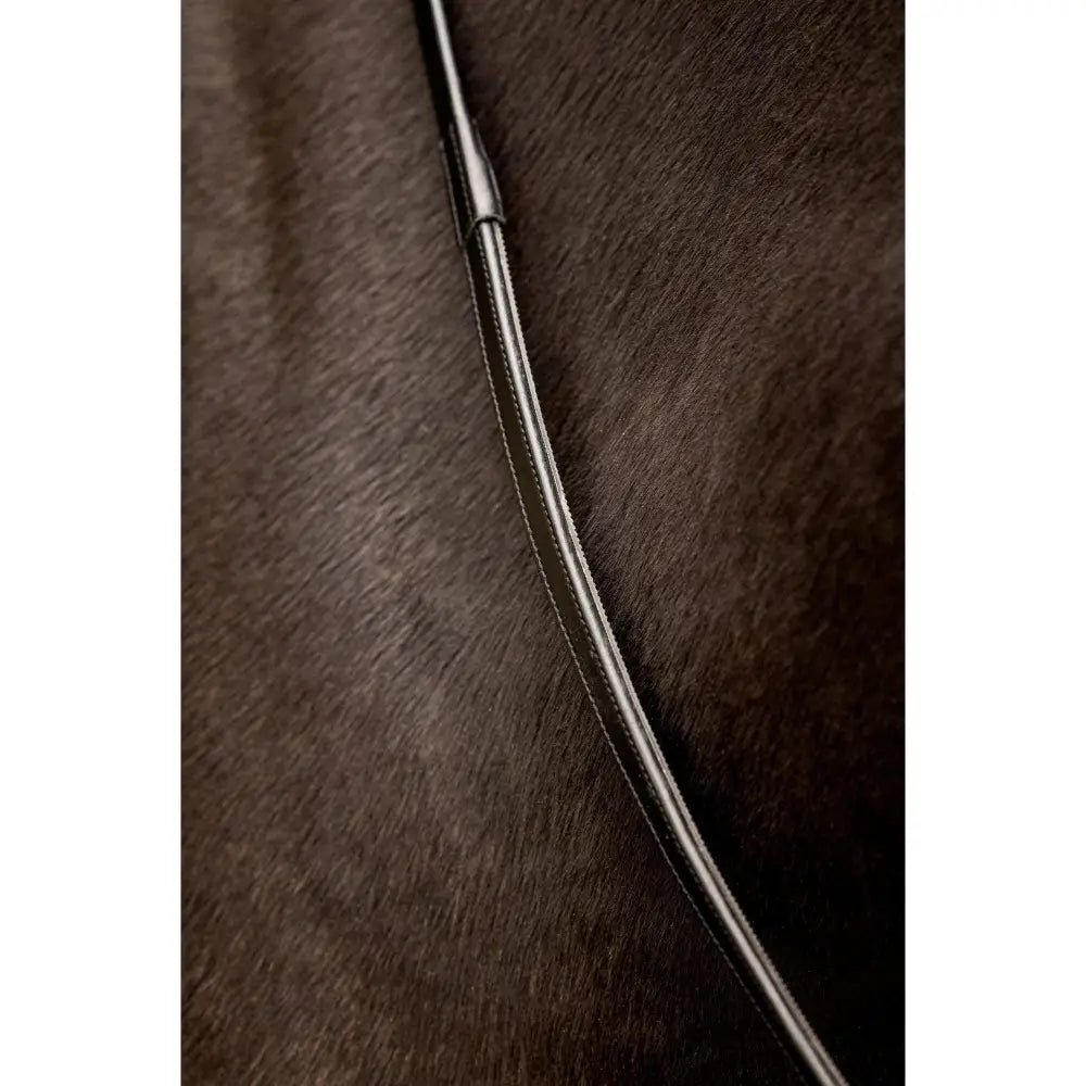 A sleek black leather horse whip with a polished metal handle paired with lemieux rubber half lined reins black silver
