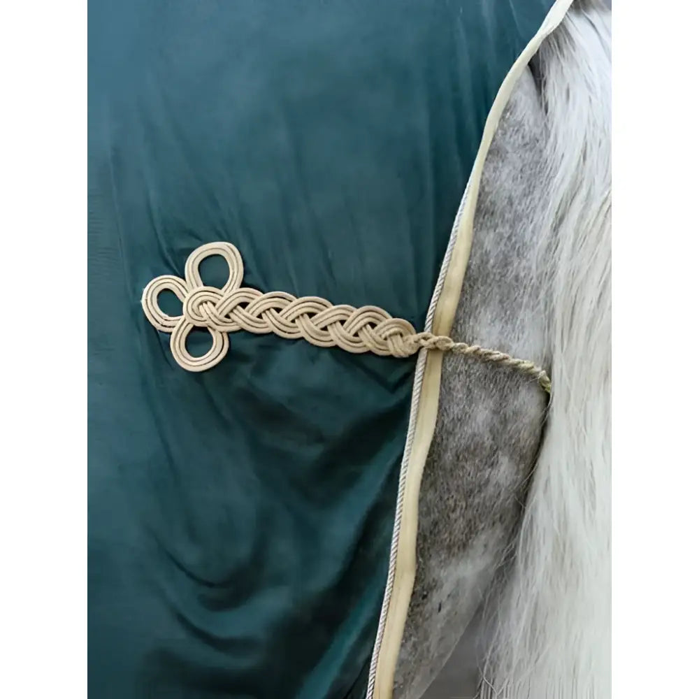 Beige braided rope tie with decorative knot on dark green fabric horse blanket lemieux scrim green design