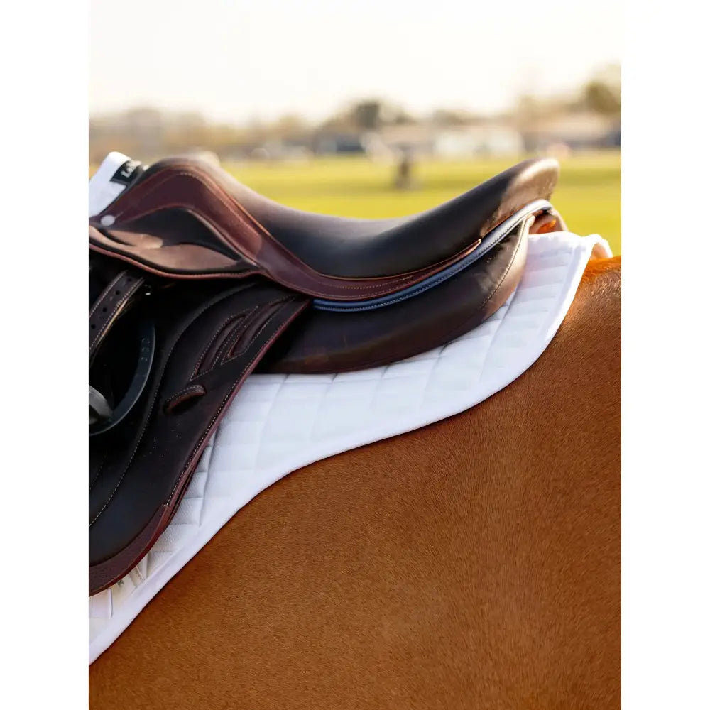 Brown leather close contact half saddle with stitched detailing resting on a white technically advanced leMieux self-cool close contact half pad