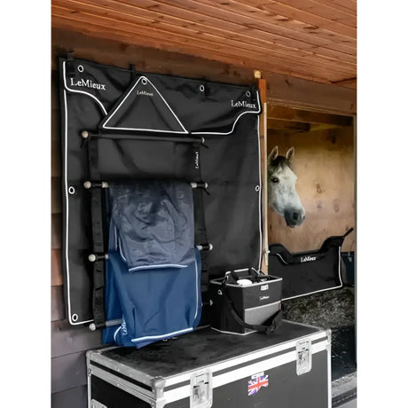 Black lemieux show stable drape black panel with white trim and blue saddle cover hanging on stable drape black