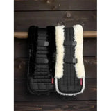 Black and white sheepskin-lined lemieux simuwool dressage girth cover black with quilted fabric and adjustable straps