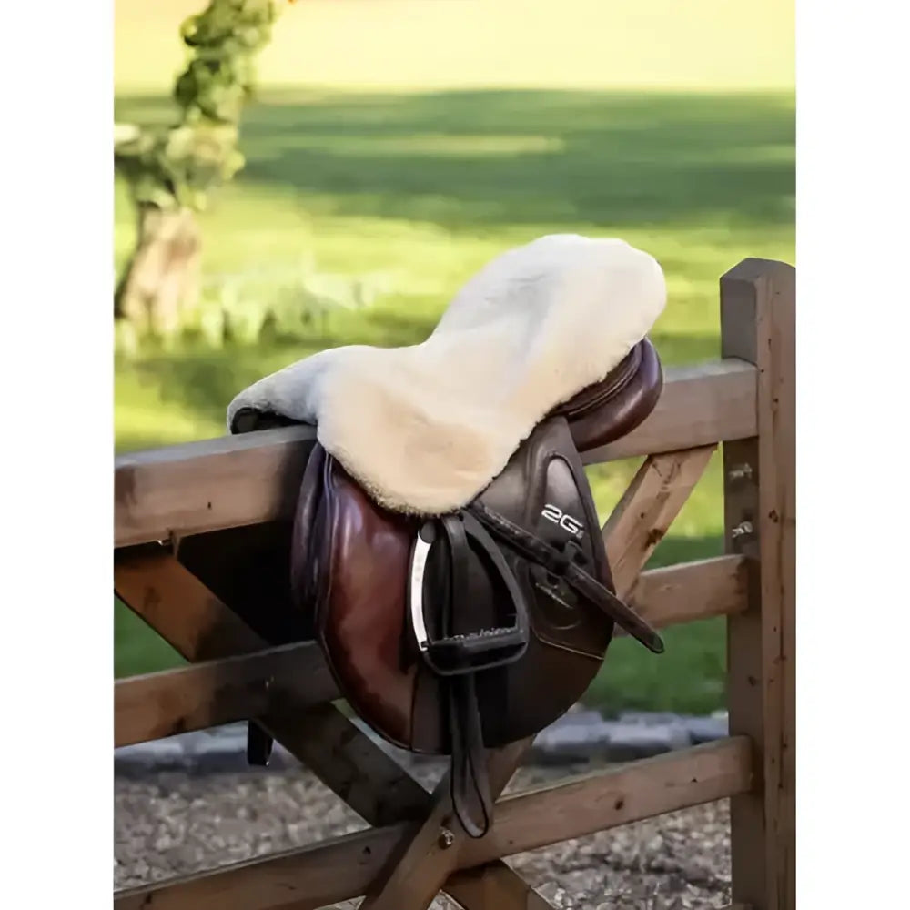 Brown leather saddle with a plush white fleece lemieux simuwool seat saver natural for extra comfort and protection