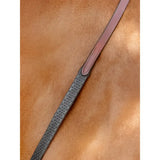 Brown leather riding crop with textured dark gray grip and stitched detailing paired with lemieux soft rubber reins chestnut silver