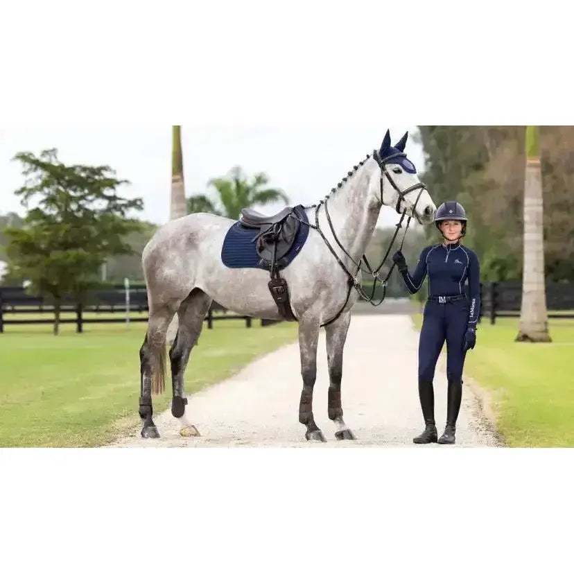 Rider stands next to dapple gray horse wearing navy lemieux soft shell anti slip eurojump square saddle pad