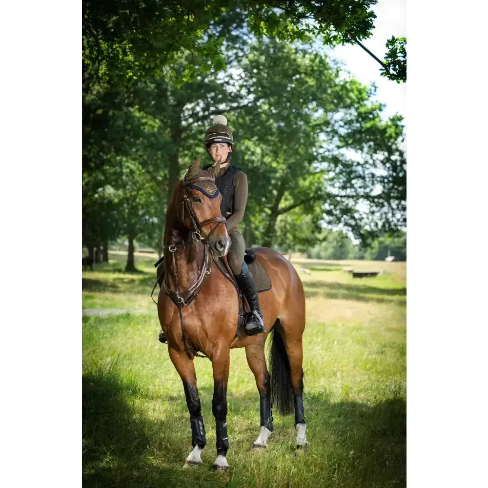A chestnut horse wearing lemieux suede close contact square alpine saddle with black leg wraps and white socks