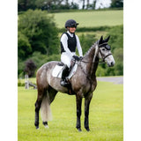 A dapple gray horse wearing a lemieux suede close contact square white suede saddle pad with black leg wraps