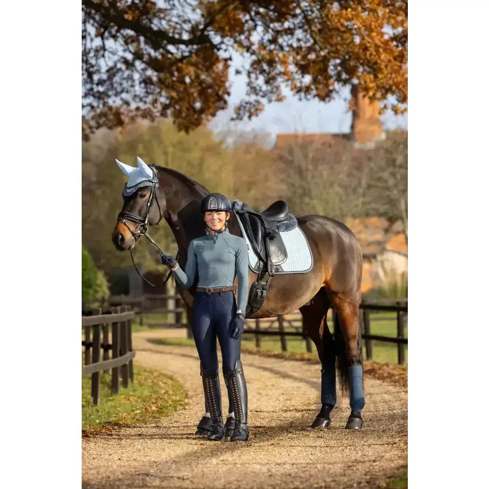 A dark brown horse with a white head cover wearing lemieux suede dressage square glacier for dressage use