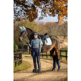 A dark brown horse with a white head cover wearing lemieux suede dressage square glacier for dressage use