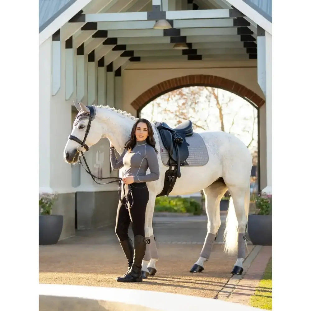 A white horse wearing lemieux suede dressage square grey with soft suede binding and gray leg wraps