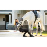 A white horse wearing a lemieux suede dressage square grey with soft suede binding and black leather tack
