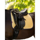 Black leather saddle rests on a tan quilted lemieux suede dressage square mimosa with dark purple trim