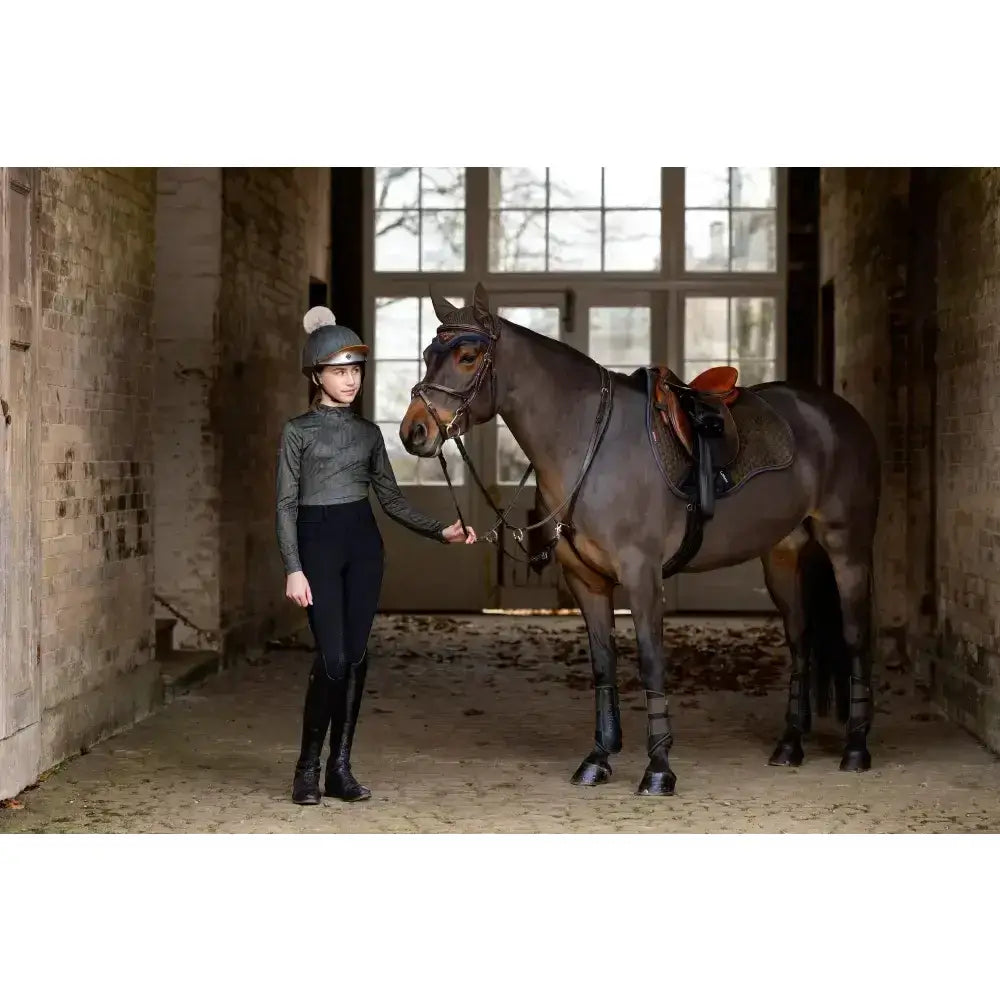 A dark brown horse stands calm in stable wearing lemieux suede gp square with high wither cut and elasticated d-ring tabs