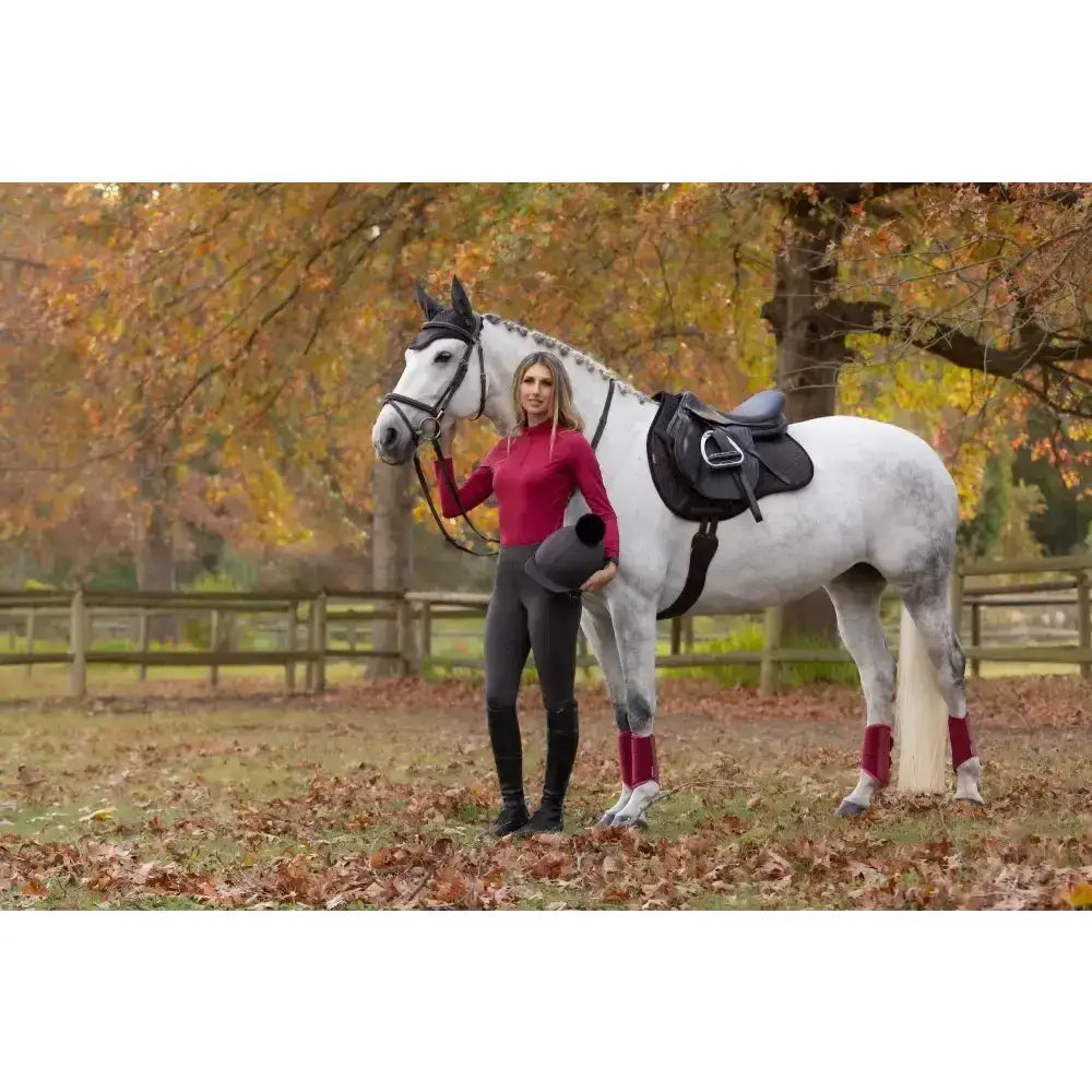 A white horse wearing a lemieux suede gp square cinder classic general purpose saddle pad in an autumn field