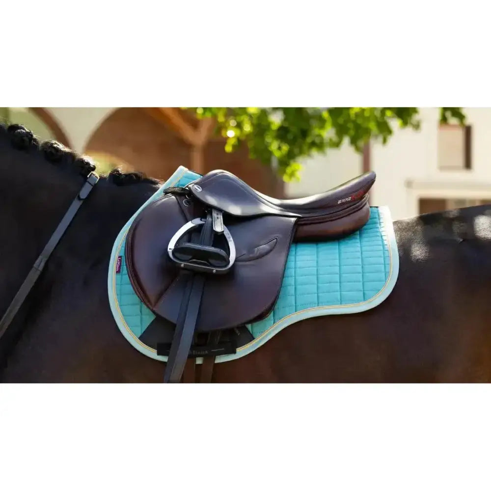 A sleek black lemieux suede gp square saddle on a quilted turquoise square lagoon saddle pad for equestrian use