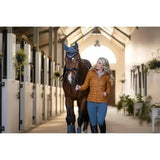 Dark brown horse wearing lemieux tilly hooded puffer jacket ginger with navy blue protective head covering and silver trim