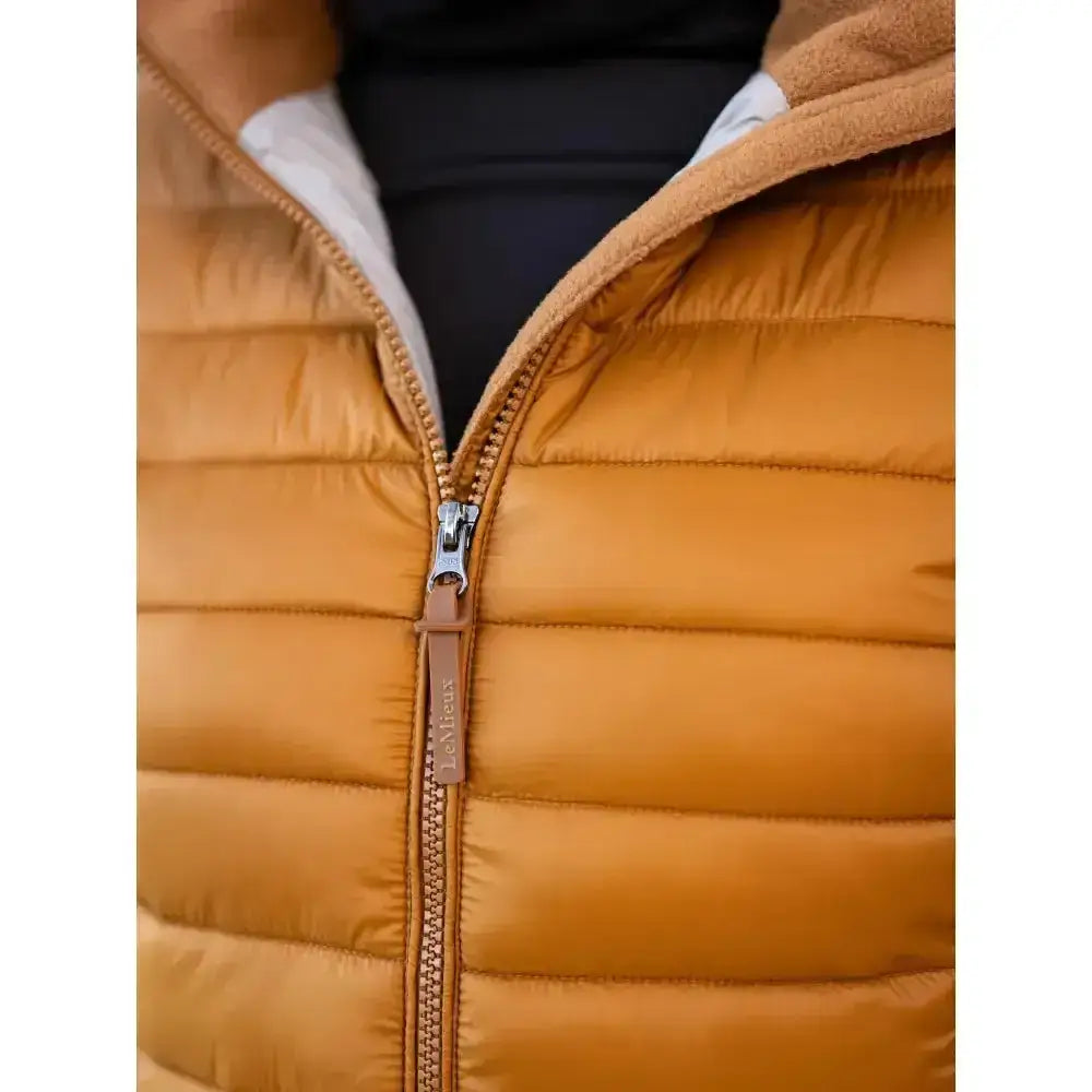 A warm mustard-yellow lemieux tilly hooded puffer jacket ginger with quilted design and tan leather zipper pull