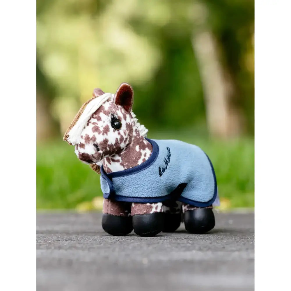 A lemieux tiny pony plush horse with white and brown spots wearing a light blue fleece tiny pony montana blanket