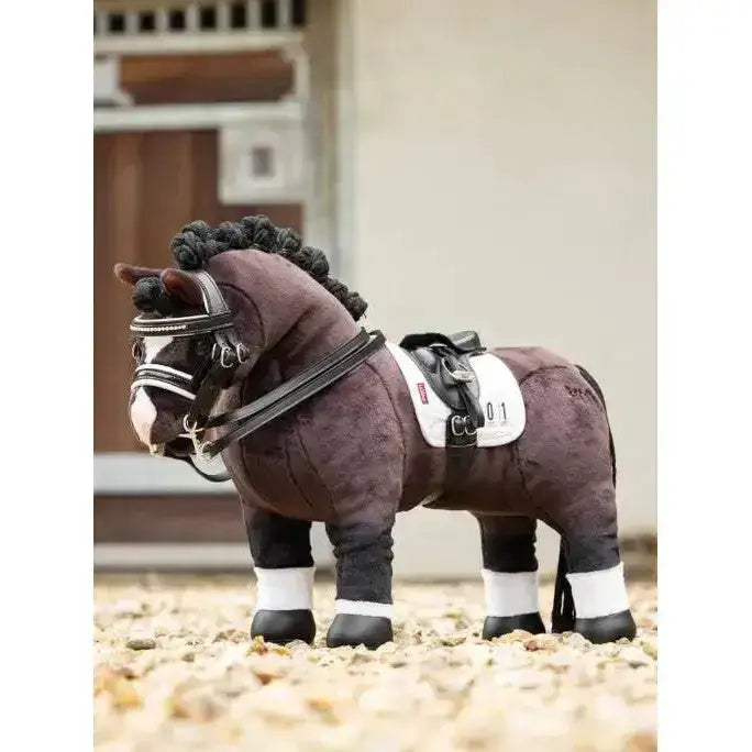 A plush brown lemieux toy pony with black braided mane, white toy pony dressage pad, and detailed bridle