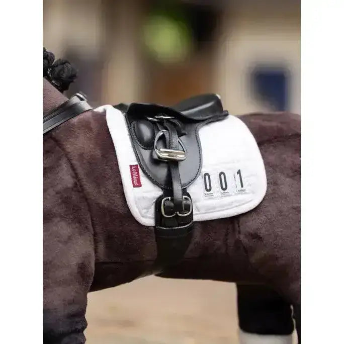 White lemieux toy pony dressage pad with black leather straps silver buckles and red brand tag on the side