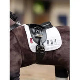 White lemieux toy pony dressage pad with black leather straps silver buckles and red brand tag on the side