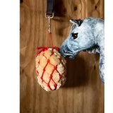 A plush light beige lemieux toy pony with a red pony haynet ember hanging from a black strap