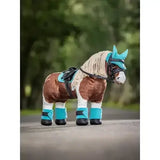 A plush brown and white lemieux toy pony wearing a turquoise pony pad azure saddle pad and matching hoof boots and bridle