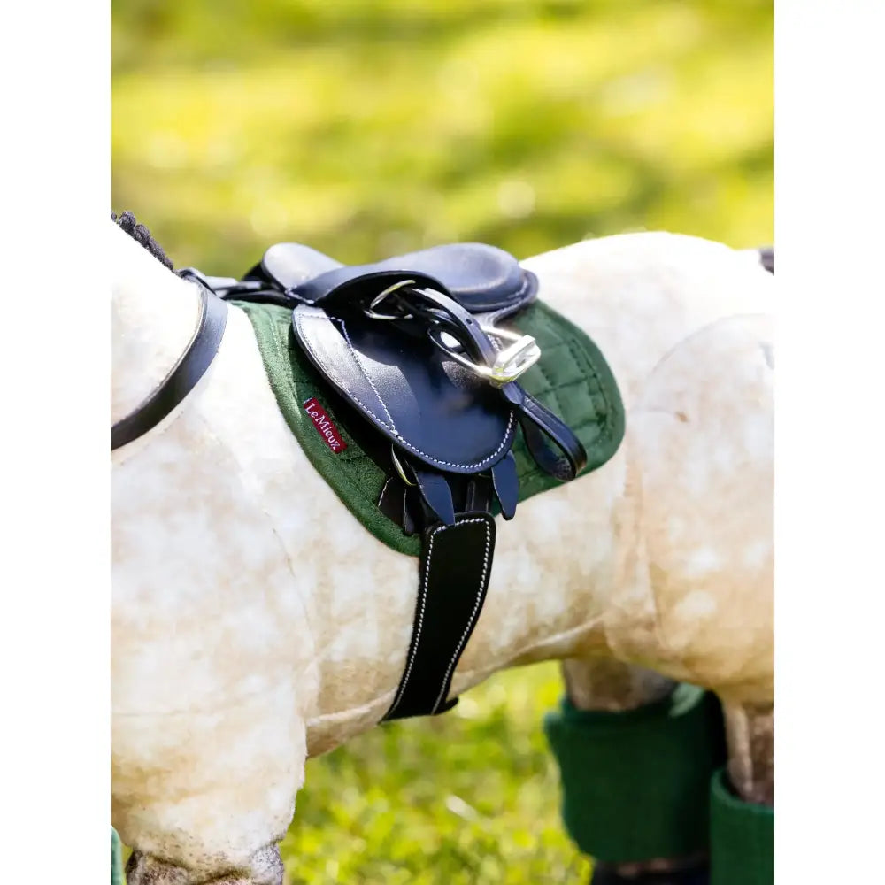 Dark blue leather saddle with silver hardware resting on a lemieux toy pony pad hunter green quilted pad