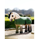 A plush white lemieux toy pony wearing a green felt toy pony rug with black trim and silver embroidery