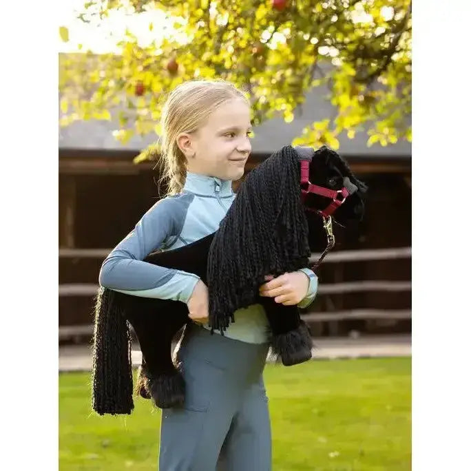 Black plush lemieux toy pony spike with long fringed mane and red halter by stable door