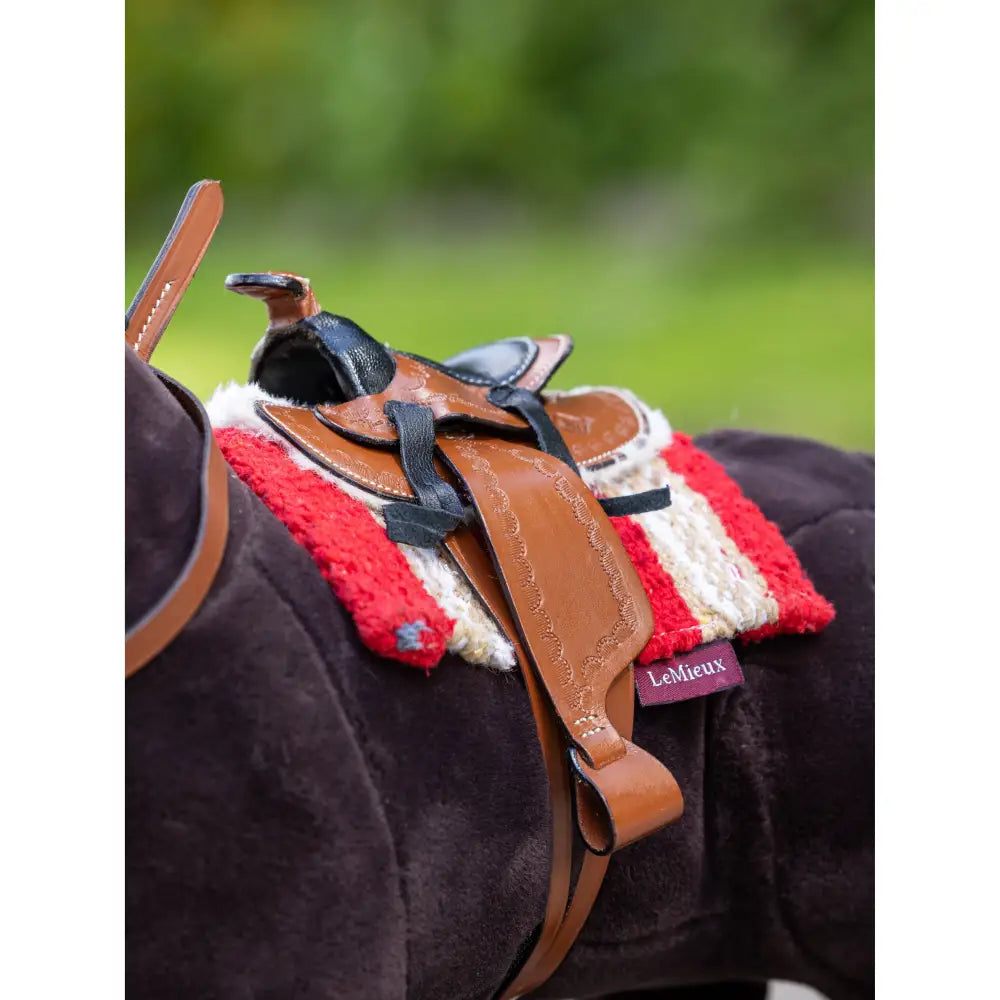 Horse saddle featuring red and white padding on a dark horse with Lemieux Toy Pony Western Pad Chilli