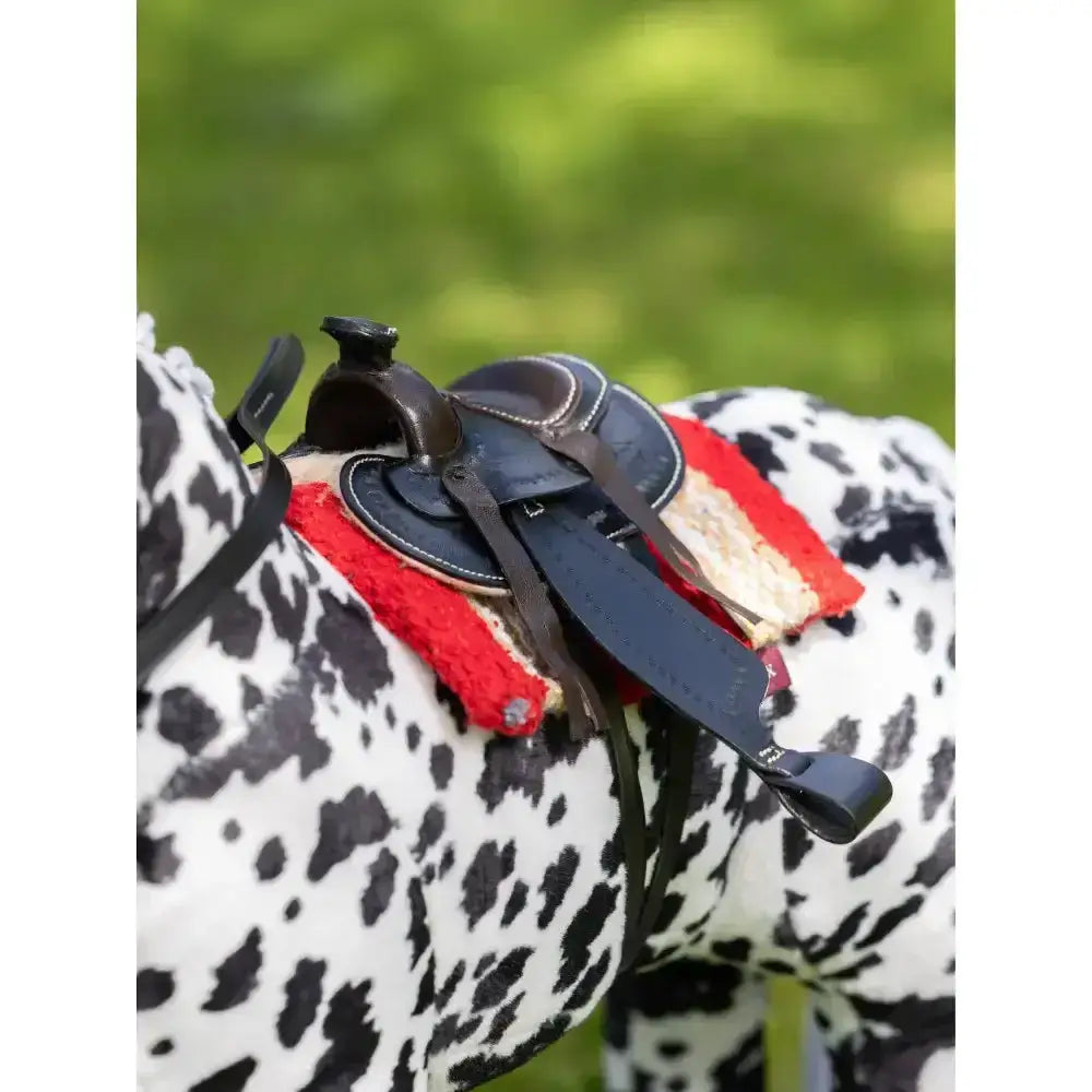 Black leather lemieux toy pony western saddle with red and white felt padding on a spotted horse figurine