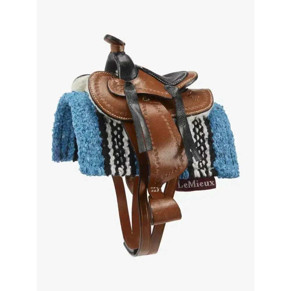 Brown leather lemieux toy pony western saddle with black accents on a blue white and black patterned blanket