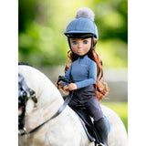 A doll wearing a lemieux toy rider outfit ice blue with a blue riding helmet and dark pants seated on a white horse