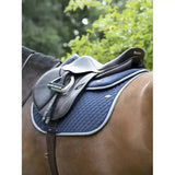 Navy blue lemieux wither relief jump pad with silver trim under dark brown leather saddle on horse back