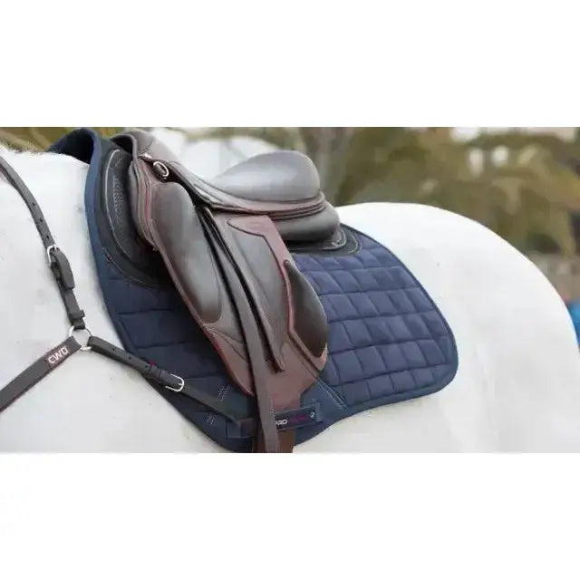 Navy blue quilted saddle pad with brown leather saddle featuring x-grip silicone design for saddle stability