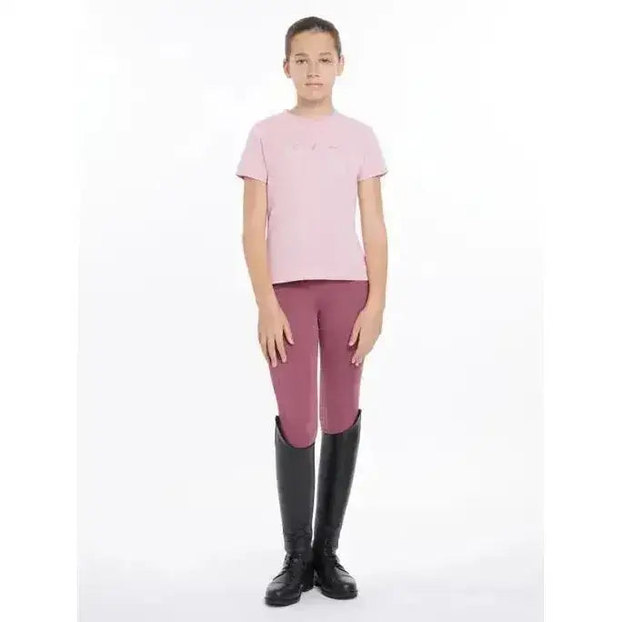 A young girl wearing a lemieux young rider arianna t-shirt blossom in light pink with hot fix silver signature lemieux autograph